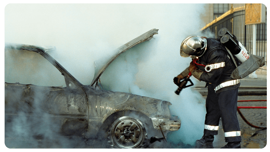 Fireman extinguishing a fire on a burning car.